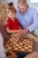 Grandparents Playing Board Game Of Draughts With Grandchildren At Home