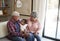 Grandparents Sitting On Sofa With Baby Granddaughter At Home