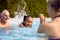 Grandparents Teaching Granddaughter To Swim On Family Summer Holiday In Pool 