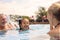 Grandparents Teaching Granddaughter To Swim On Family Summer Holiday In Pool 