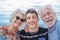 Grandparents with teenage boy grandson hugging each other at the sea having fun together and smiling happily