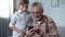 Grandson explaining grandfather how to use smartphone, easy app for elderly