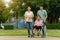 grandson and granddaughter pushing senior woman in wheelchair at park