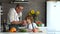 Grandson and grandfather cook together in the kitchen. An elderly man gives to try a salad boy. Healthy lifestyle