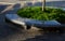 Granite bench in the park in the shape of a circle of gray polished granite stone. inside is a flower bed with ornamental shrubs.