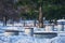 Granite benches in a snowy winter park under a pine tree. Unusual design of cylindrical seats and tables. Paths cleared