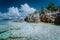 Granite boulders in shallow ocean water and white cloudscape on amazing Anse Source D`Argent tropical beach, La Digue