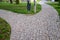 Granite paving of irregular sections of chipped stone around a park with green lawn gray color of the pedestrian path