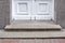 Granite threshold at the entrance door made of white wood and gray facade.