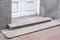 Granite threshold at the entrance door made of white wood and gray facade.