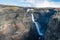 Granni waterfall in the Icelandic highlands during blue cloudy sky with rainbow. Tourist with blue jacket watching the scenery.