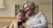 Granny and granddaughter sitting on couch having fun using smartphone