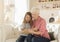 Granny reading interesting book together with her cute little granddaughter indoors, blank space