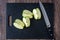 Granny Smith apple quartered on a black cutting board with a chef knife