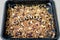 Granola in a black baking sheet. The inscription in wooden letters Granola
