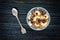 Granola with cashew in a bowl, a teaspoon. Black wooden table