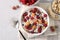 Granola crispy honey muesli with natural yogurt, fresh red and yellow raspberries, chocolate and nuts in a bowl on gray background