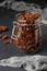 Granola crispy muesli with natural honey, chocolate and nuts in a glass jar against a dark background, healthy food, vertical