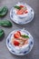 Granola, muesli with strawberries and yogurt decorate with mint in a ceramic bowls on wood grey background