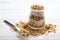 Granola superfood with almond and cashew nuts, dry fruits, raisins cherry in the glass jar on the white wooden table, top view, br