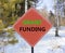 Grant funding symbol. Concept words Grant funding on beautiful red road sign. Beautiful forest snow blue sky background. Business
