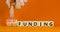 Grant funding symbol. Concept words Grant funding on beautiful wooden blocks. Beautiful orange table orange background.