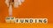 Grant funding symbol. Concept words Grant funding on beautiful wooden blocks. Beautiful orange table orange background.