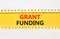 Grant funding symbol. Concept words Grant funding on yellow paper. Beautiful yellow table white background. Business and grant