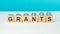 grants text on wooden blocks with coins on blue background