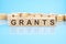 grants - text of on wooden cubes, reflected from the bright blue surface