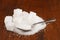 Granulated white sugar in a spoon with some cubes on a brown wooden background