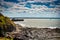 Granville, France - June 29, 2012. The wall of the port near cliff with small lighthouse in sea