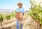 Grape farmer holding fruit basket from crops harvest and walking on farm, estate or pasture. Happy woman and garden