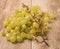 Grape fruit stem alone in front of heap of green grapefruit on wooden table.