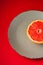 Grapefruit half on grey plate, tropical creative minimal food fruit concept, on vibrant red background