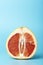 Grapefruit minimal erotic concept. Half a juicy grapefruit close up on a colored background