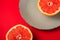 Grapefruit near to grey plate with fruit half of fruit, tropical creative minimal food concept