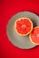 Grapefruit two half on grey plate, tropical creative minimal food fruit concept, on vibrant red background