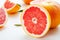 Grapefruits whole and halves on a white table. Fruit composition of useful citrus diet fruits