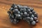 Grapes. A bunch of dark, black grapes lies on a wooden board close-up