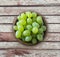 Grapes in a wooden bowl isolated on wooden table. Green grapes Kish Mish with copy space for text. Ripe and tasty grapes on a wood