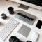 Graphics tablet, camera, laptop, black cup, objects, keyboard, mobile phone and wireless mouse on a white wooden table.