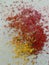 Graphite shavings of yellow and red colors with some brown spread on a white background