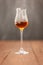 Grappa glass with brandy or sherry or calvados on wooden table with light grey background.