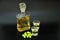 Grappa, strong alcohol in a bottle and two glasses, next to a bunch of green grapes on a black background