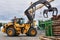 Grapple loader unloads logs onto a feed conveyor in the yard of a woodworking plant