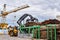 Grapple loader unloads logs onto a feed conveyor in the yard of a woodworking plant