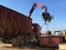 A grapple truck loads scrap industrial metal for recycling.