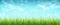 Grass and blue sky with clouds, bokeh. Spring background. Panorama.