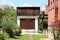 Grass covered concrete driveway leading to narrow old garage with locked wooden doors and storage area on top